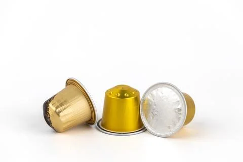 Close-up on white background lie three golden capsules for coffee of different Stock-Fotos