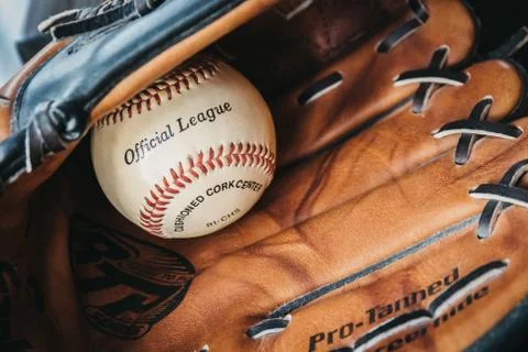 Close up of a white baseball ball inside tan baseball glove. Stock Photos