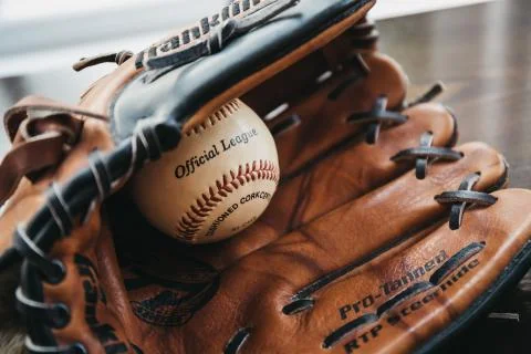 Close up of a white baseball ball inside tan baseball glove. Stock-Fotos