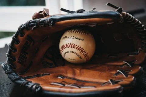 Close up of a white baseball ball inside tan baseball glove. Stock Photos