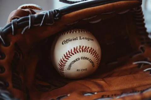 Close up of a white baseball ball inside tan baseball glove. Stock Photos