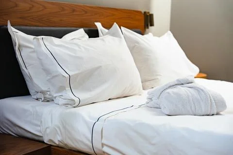 Close-Up Of White Bed With Soft Pillows And Wooden Headboard Stock Photos