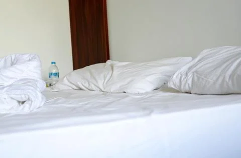 Close-up of white bedding sheets and pillow against the background of a hotel Foto stock