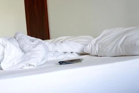 Close-up of white bedding sheets and pillow against the background of a hotel Stock Photos