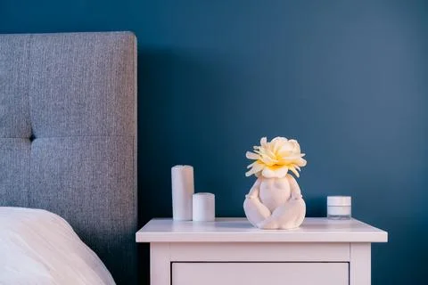 Close up white bedside table with ceramic female body-shaped vase with rose Stock Photos