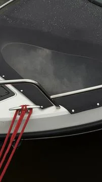 Close-up of a white boat bow featuring a shiny metal cleat tied with a bright Stock Photos