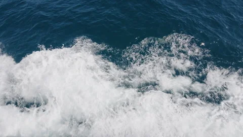 Close-up of white boat wake and sea foam churning across blue water, Cote Stockbeeldmateriaal 344812225