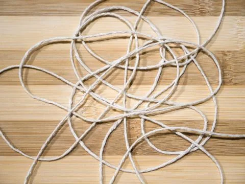 Close-up of white braided roll of thin white string or yarn unraveled and tan Stock Photos
