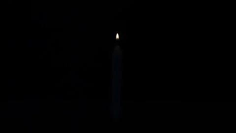 Close up of white candle being lit and burning brightly in pitch black dark. Stock Footage 329948762