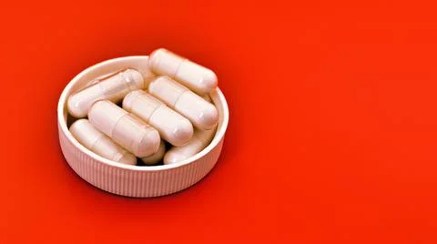 Close-up of white capsules on orange background Stock Photos