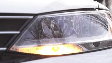 Close-up of a white car headlight with a flashing turn signal. The car alarm is Stock Footage 264094676