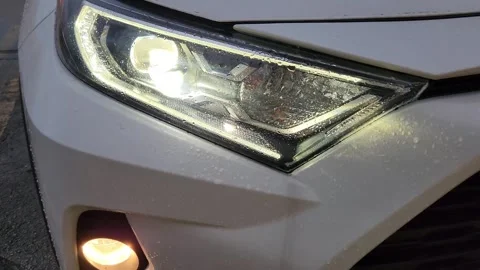 Close-up of white car LED low beam headlight with fog light turned on Stock Footage 327067292