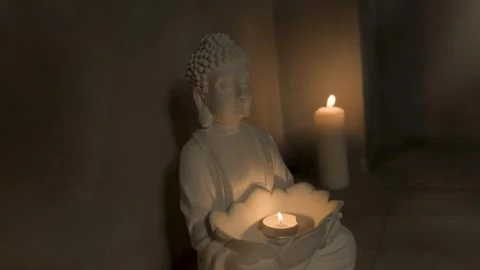 Close-up of a white ceramic Buddha statue among candles Video stock 305402265