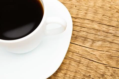 Close up of white ceramic coffee cup on wooden table - view from top 写真素材