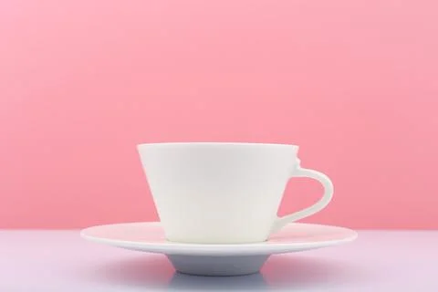 Close up of white ceramic coffee cup with saucer on white table against bright Stock Photos