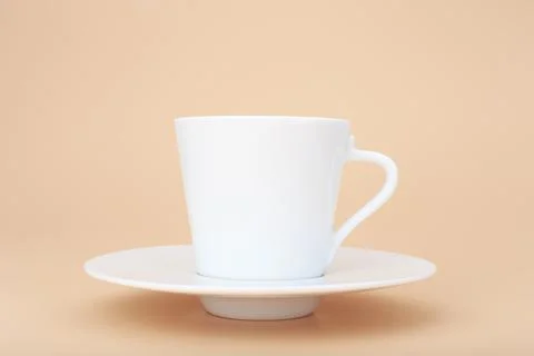 Close up of white ceramic coffee cup with saucer against pastel beige background Stock Photos