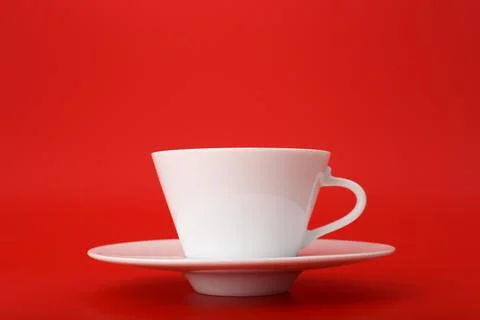 Close up of white ceramic coffee or tea cup with saucer isolated on bright red Stock Photos