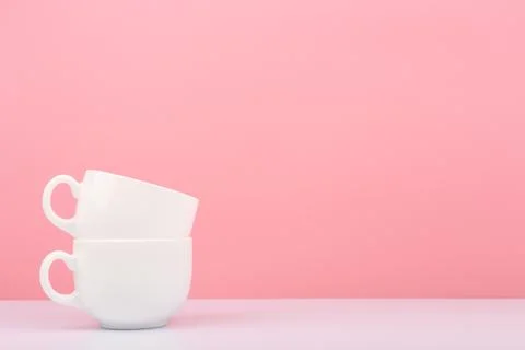 Close up of white ceramic cup in another against pink background with copy space Stock Photos