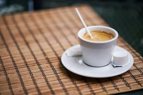 Close-up of a white ceramic cup filled with aromatic espresso on a bamboo p.. 스톡 사진