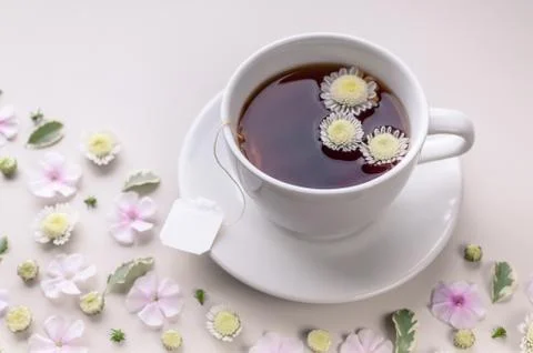 Close-up white ceramic cup with tea on a floral pattern on a beige background Stock Photos