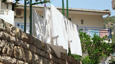 A close-up of a white cloth dries on a rope under the sun outside against the Stock Footage 202076630