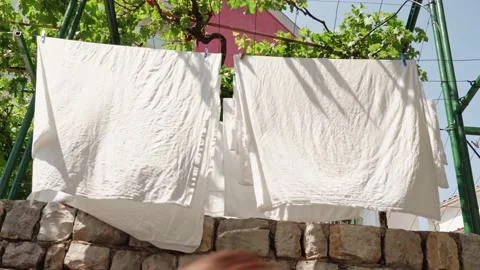 A close-up of a white cloth dries on a rope under the sun outside against the Stock Footage 202076685