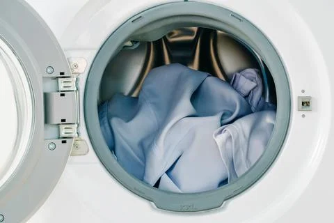 Close up white clothes in washing machine background. Laundry concept. Stock Photos