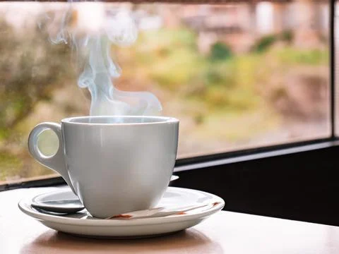 Close up of a white coffee cup on a bar table with a window in the background Stock Photos