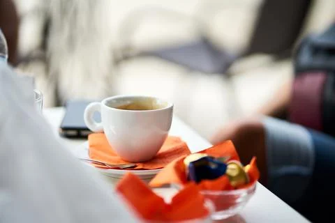 Close-up of a white cup of coffee with orange napkins on table 写真素材