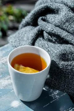 Close up white cup of lemon tea wrapped in blanket Stock Photos