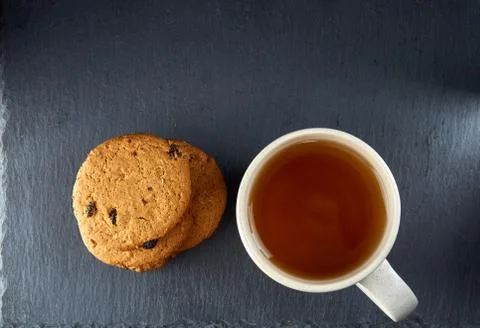 Close-up white cup of tea with chocolate cookies on dark background, top view Stock Photos
