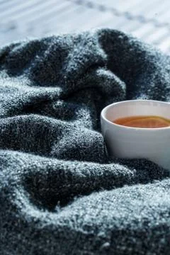 Close up white cup of tea wrapped in blanket Stock Photos
