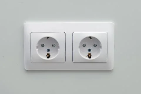 Close up of a white double electrical power outlet on a light gray wall. Mode Stock Photos