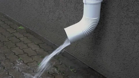 Close-up of a white drain pipe gushing water on the sidewalk during the rain Stock Footage 124113947