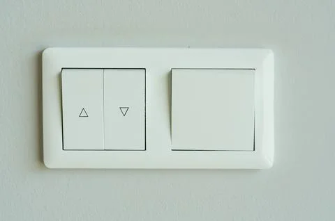 Close-up of white electric light switch on white wall background. Stock Photos