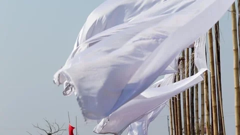 Close-up of white fabric flags waving on bamboo poles in wind Stock Footage 331276870