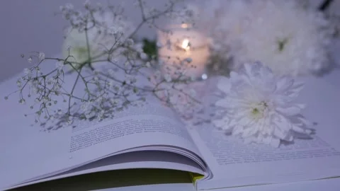 Close-up white flowers on an open book.burning candle. chrysanthemum. gypsophila Stock Footage 260417782