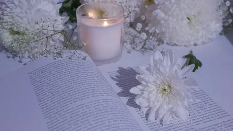 Close-up white flowers on an open book.burning candle. chrysanthemum. gypsophila Stock Footage 260417800