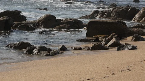 Close up of white foamy waves lap on the rocky beach with sand Stock Footage 103637515
