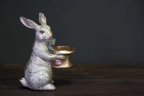 Close-up of a white-golden statuette of an Easter bunny holding a empty hat,  Foto stock