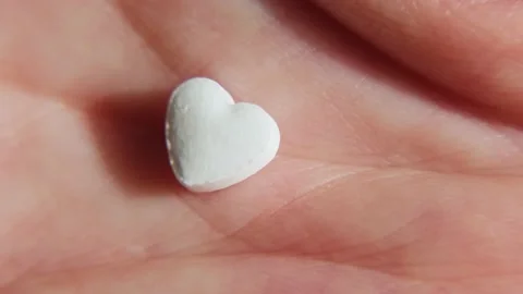 Close-up white heart-shaped tablet in human palm. Stock Footage 201575100