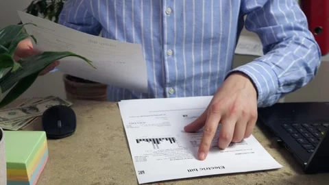 Close up of white male's hands looking at bills, including electricity Stock Footage 308400733