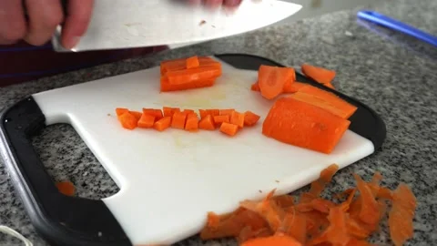 Close-up of a white man's hands cutting a carrot into small squares with a knife Video stock 181773642