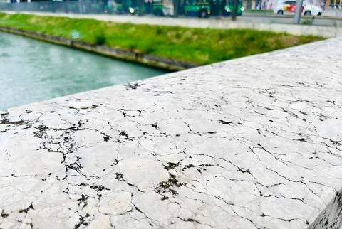 Close-Up of White Marble Ledge with Dark Veins Overlooking Green Canal and .. Stock Photos