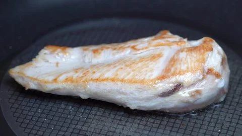 Close up of white meat chicken cutlets grilling on a griddle pan Stock Footage 87381015