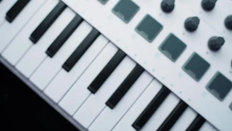 Close-up of a white MIDI keyboard controller with piano keys, pads and knobs on Stock Footage 331488411