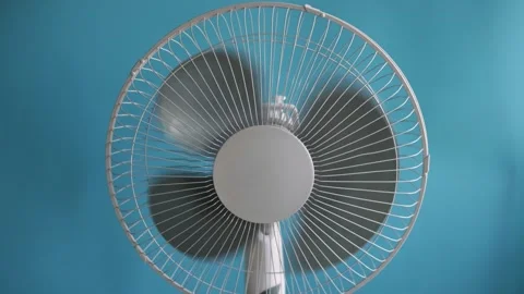 Close-up of a white oscillating fan spinning against a vibrant blue background Stock Footage 340266579