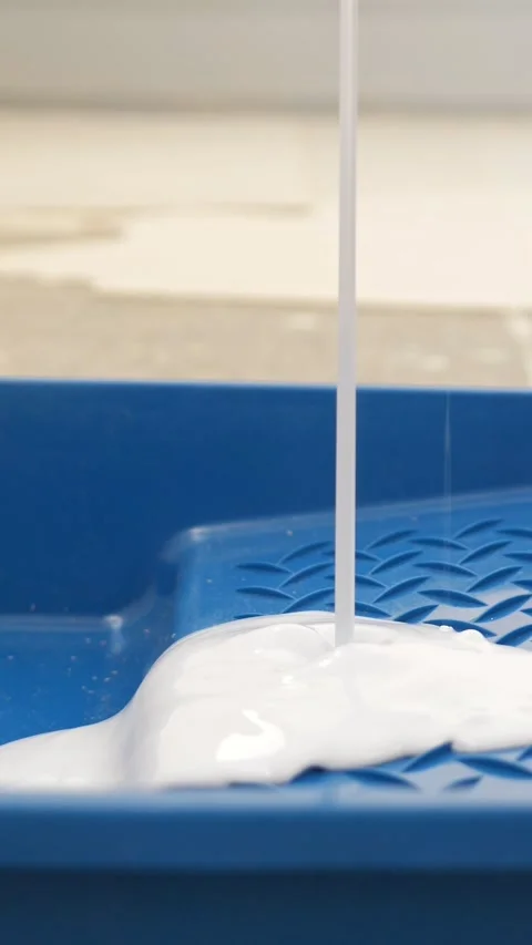 Close up of white paint pouring into a blue plastic tray for wall painting Stock-Footage 341580466