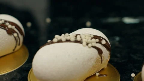 Close up of white pastries lying in a row and being decorated with chocolate. Stock Footage 89959444