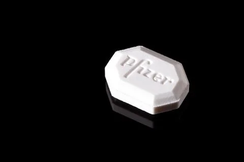 Close-up of white Pfizer tablet on black background. Illustrates modern pha.. Foto stock